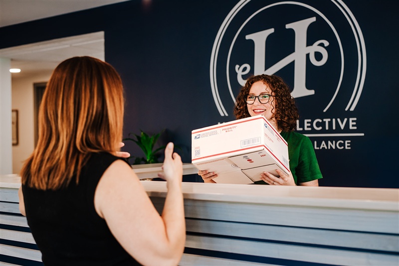 Haven Collective staff member at the front desk receiving business mail packages for a member, illustrating professional mail handling and virtual business address services.